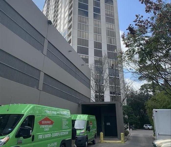 a high rise building with green vans surrounding it